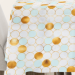 Tischdecke mit geometrischem Kreismuster in Gold und Pastellblau auf hellem Hintergrund, ideal für eine luxuriöse und moderne Tischdekoration.